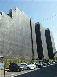 大規模修繕で足場とメッシュシートに覆われたマンションの全景